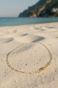 Alessia 18K gold-filled beaded chain necklace laid on warm Mediterranean sand, Amalfi Lane